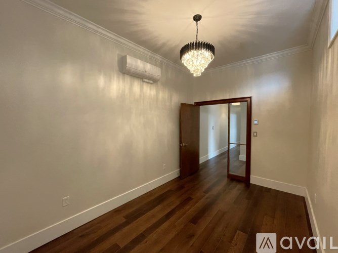 A hallway with wooden floors and a chandelier hanging from the ceiling.