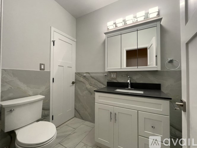 A bathroom with a toilet, sink, and a mirror cabinet.