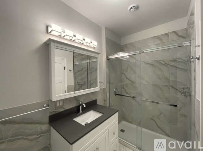 A bathroom with a sink, mirror, and shower.