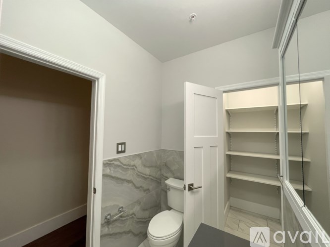 A bathroom with a toilet, sink, and a marble wall.
