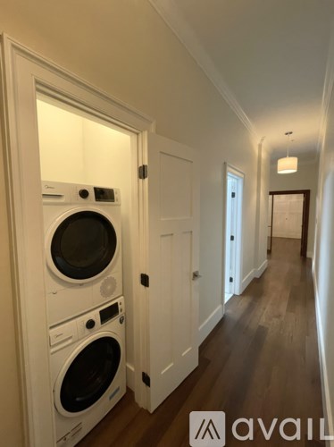 A hallway with a washer and dryer in the doorway.