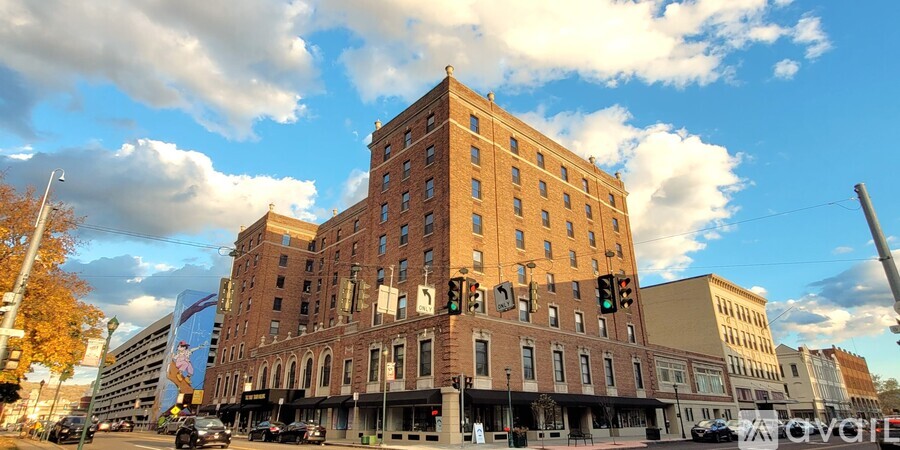 A large red brick building with many windows is in the middle of a street.