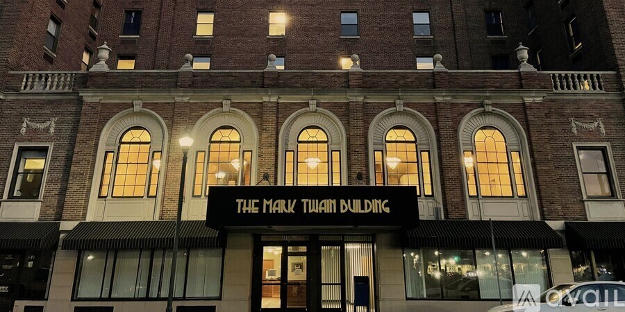 The Mark Twain Building is a large, historic building with a black awning and white trim.