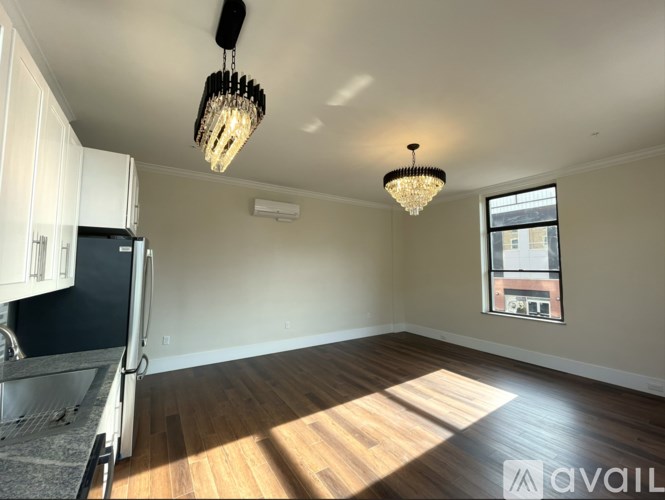 A well-lit, empty room with wooden floors and a large window.
