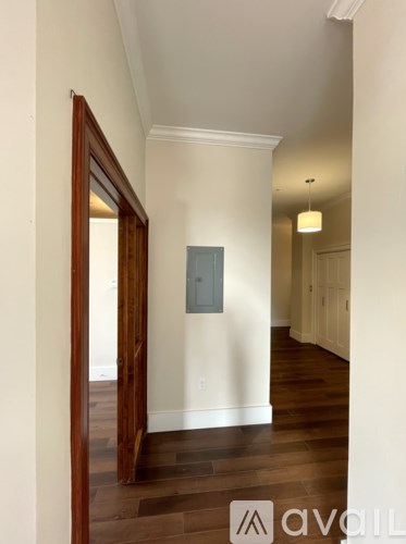A hallway with wood floors and white walls.