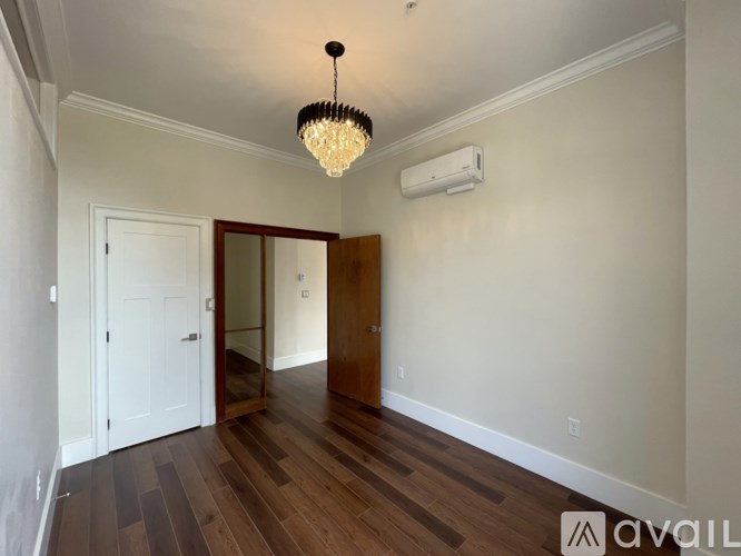 A room with a wooden floor and a chandelier hanging from the ceiling.