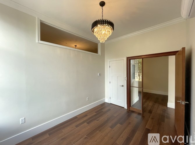 A room with wooden floors and a chandelier hanging from the ceiling.
