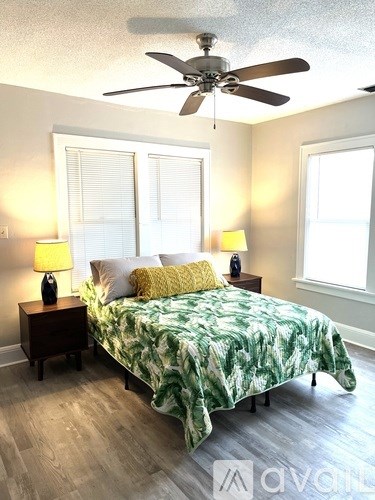 A bedroom with a bed, two lamps, and a ceiling fan.