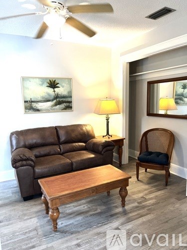 A living room with a brown leather couch, a wooden coffee table, and a painting on the wall.