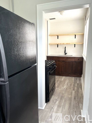 A black fridge is in a kitchen with a wooden cabinet and a stove.