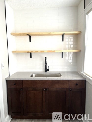 A kitchen with a sink and wooden shelves.