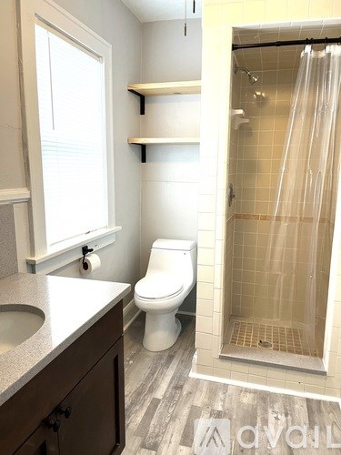 A white toilet sits in a bathroom next to a walk-in shower.