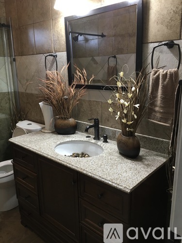 A bathroom with a sink, mirror, and vases on the counter.