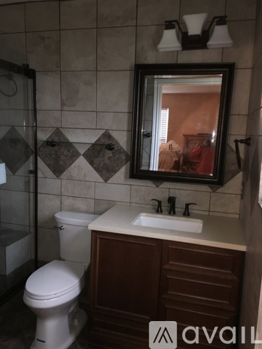 A bathroom with a toilet, sink and mirror.