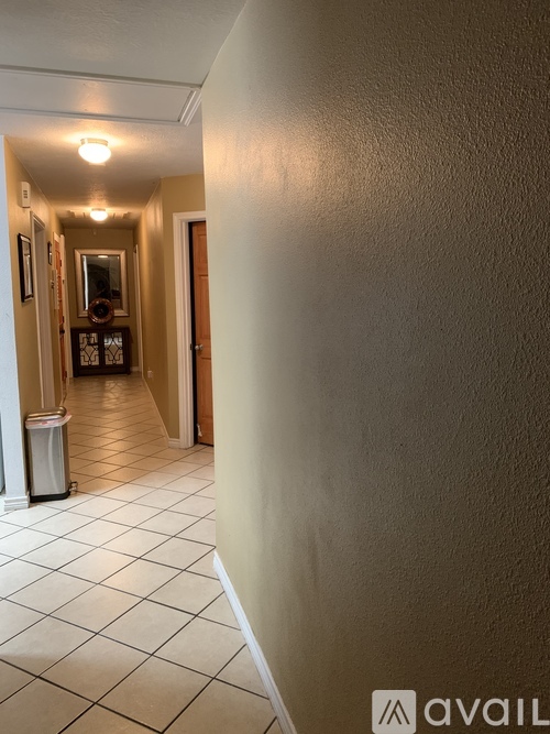 A hallway with a trash can and a mirror on the wall.