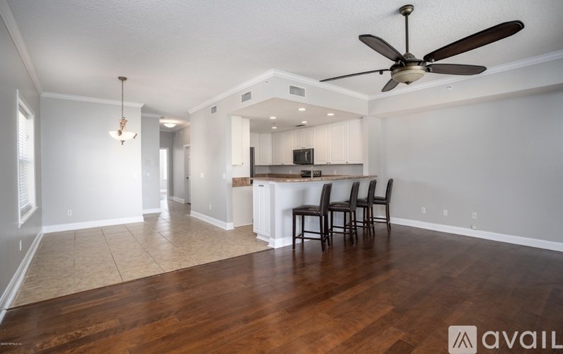 A living room with a brown floor and a ceiling fan.