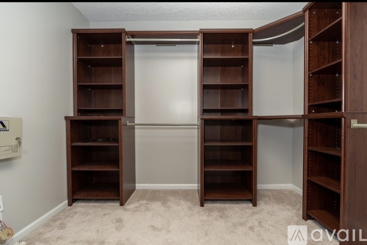 A room with a white wall and a large open closet with shelves.