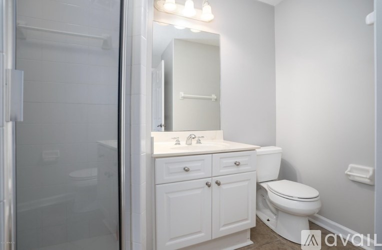 A white bathroom with a toilet, sink, and mirror.