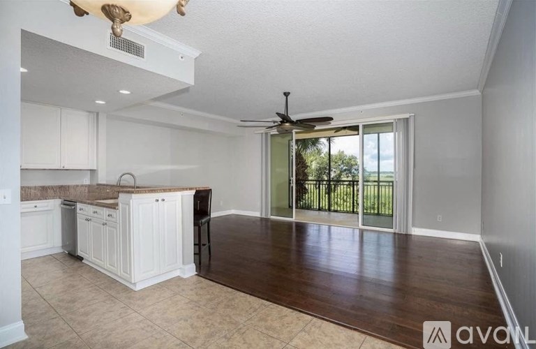 A spacious kitchen and living room with a sliding glass door leading to a balcony.