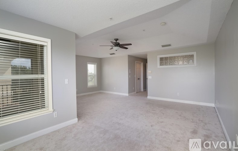 A spacious room with a ceiling fan and a window with blinds.