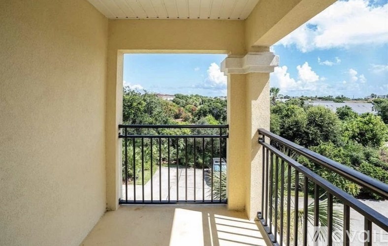 A balcony with a view of a green landscape and a body of water.