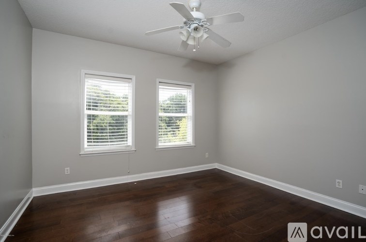 A room with a ceiling fan and two windows.