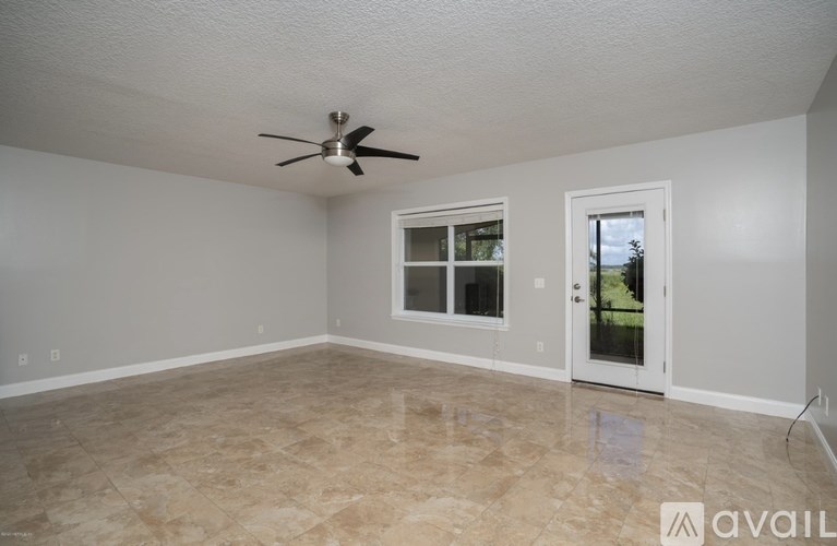 A room with a ceiling fan and a door leading to a patio.