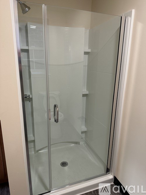 A shower stall with a glass door and a handle.