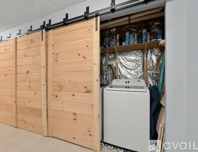 A white washing machine is in front of a wooden wall.