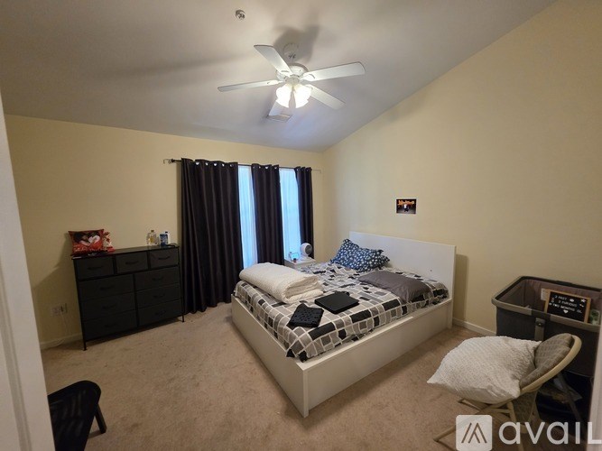 A bedroom with a bed, chair, and ceiling fan.