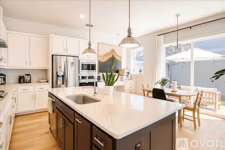 A kitchen with a large island and pendant lights.