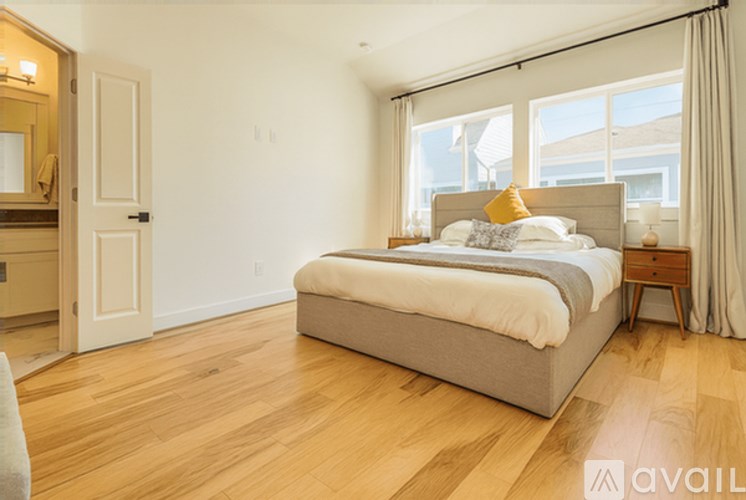 A bedroom with a large bed and wooden floors.