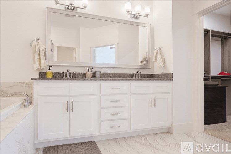 A bathroom with a marble countertop and white cabinets.