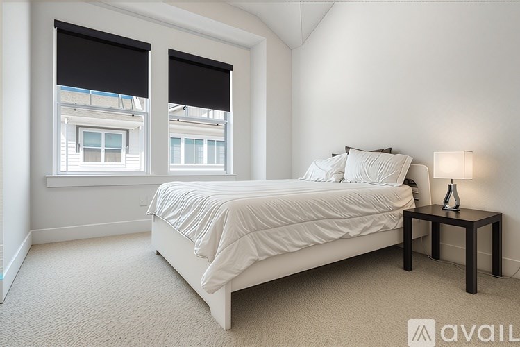 A bedroom with a bed, nightstand, and window with blinds.