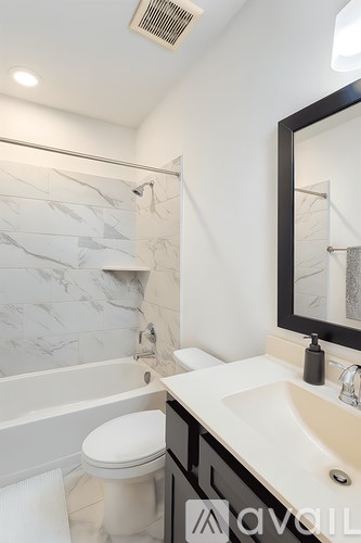 A bathroom with a marble tile shower and a white toilet.