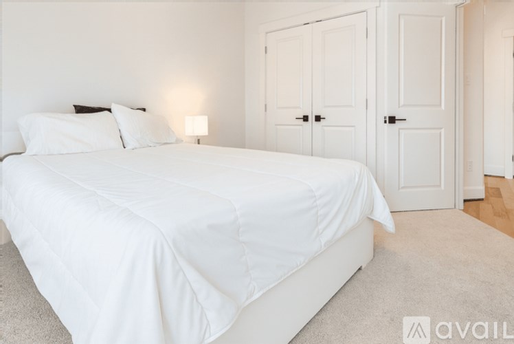 A white bed with a white comforter and two white pillows.