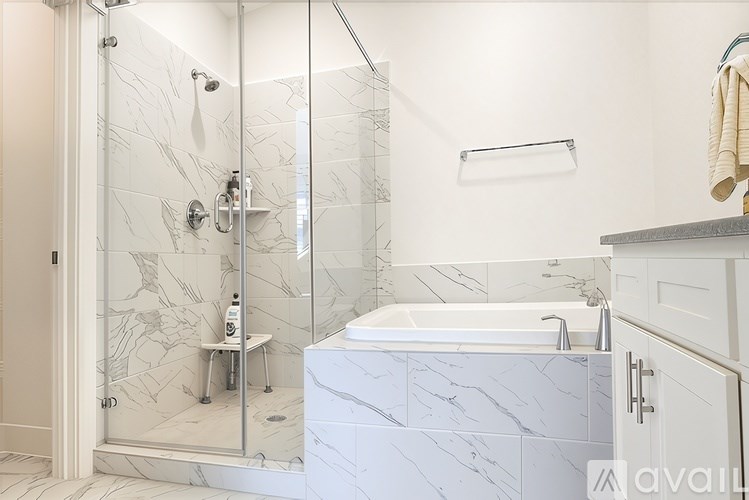 A white marble bathroom with a walk-in shower and a white bathtub.