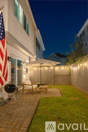 A backyard with a patio, a grill, and a flag.