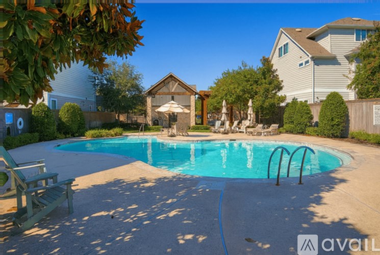 A pool surrounded by a concrete patio and a stone wall.