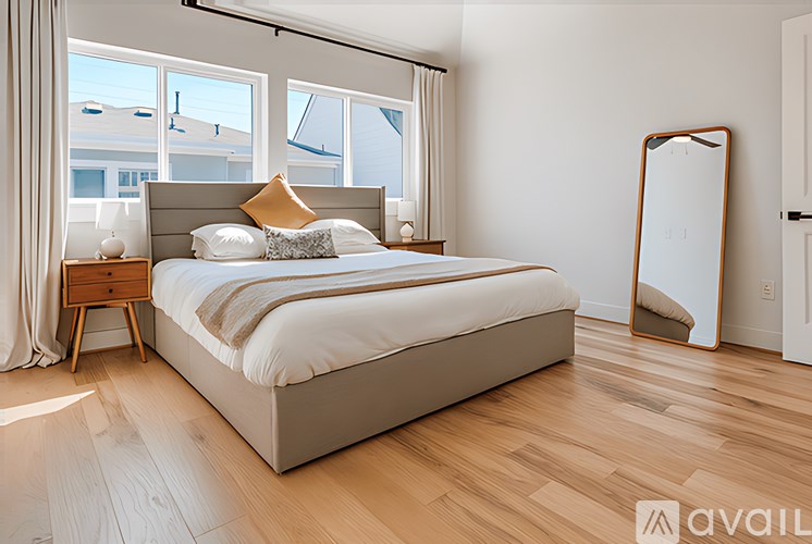 A bedroom with a large bed and wooden flooring.