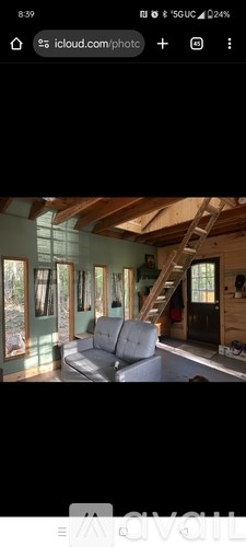 A room with wooden beams on the ceiling and a grey couch.