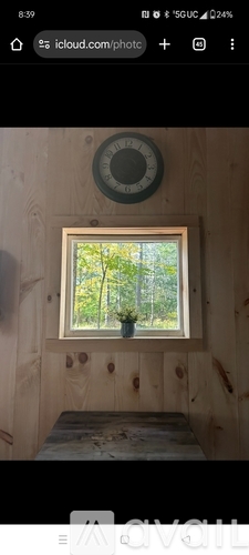 A small window in a wooden room with a view of trees outside.