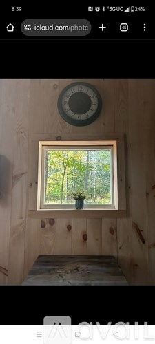 A small window in a wooden room with a view of trees outside.
