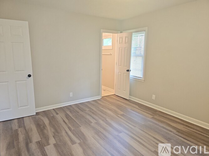 A room with wooden flooring and two doors, one of which is open.