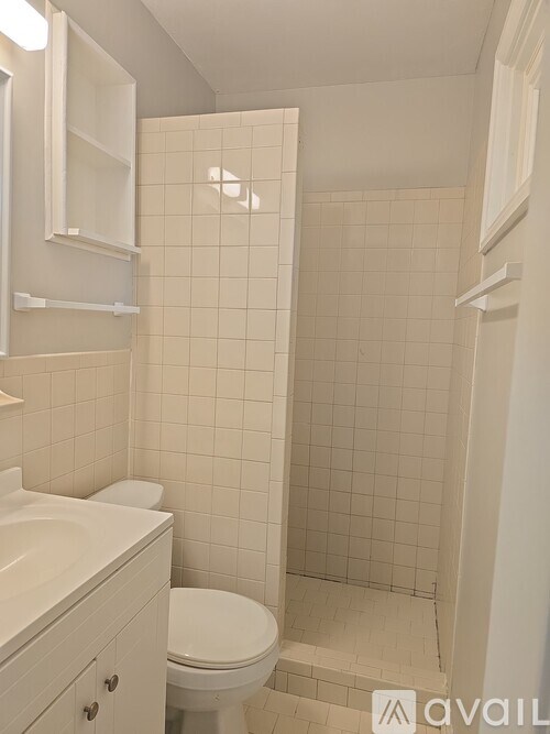 A white bathroom with a toilet, sink, and shower.