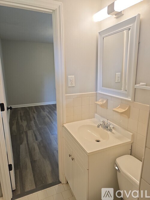 A bathroom with a sink, toilet and mirror.