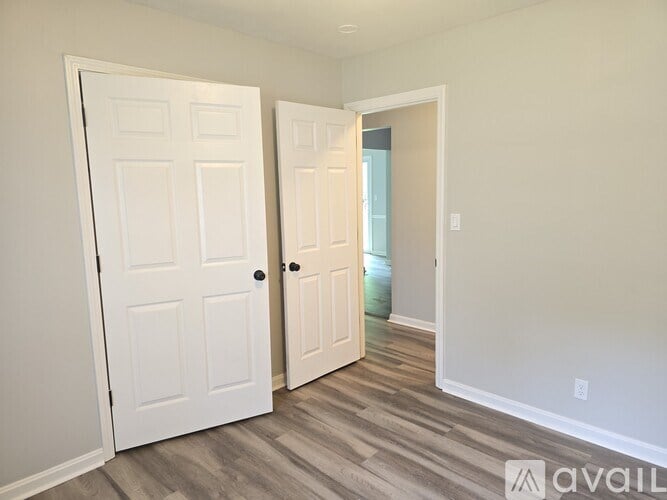 A room with two white doors and a wooden floor.