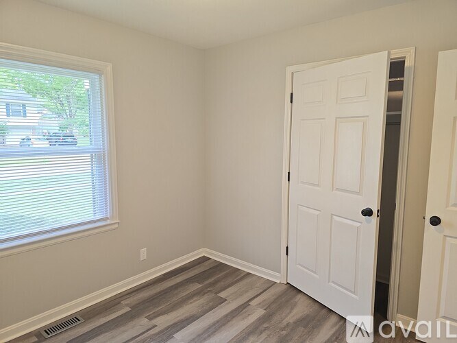 A room with a white door and a window with blinds.