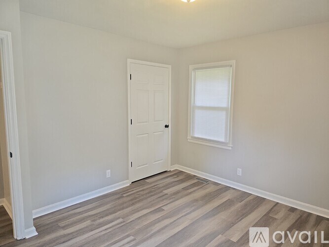 A room with a white door and a window with blinds.