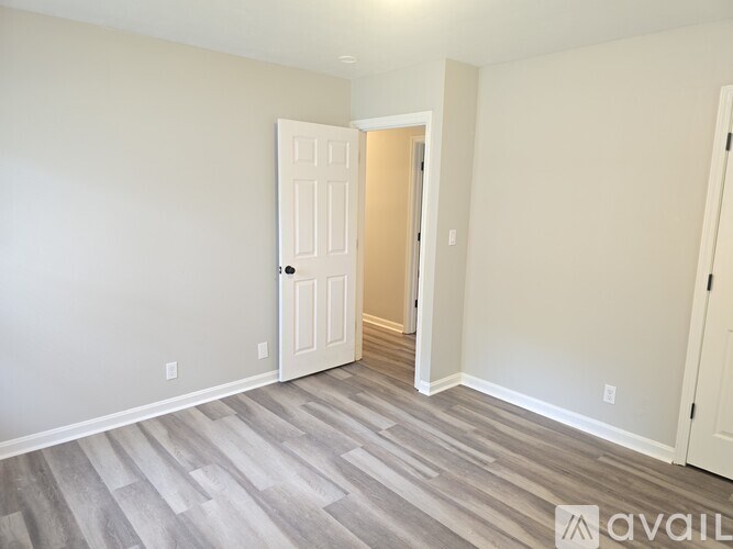 A room with a white door and a wooden floor.